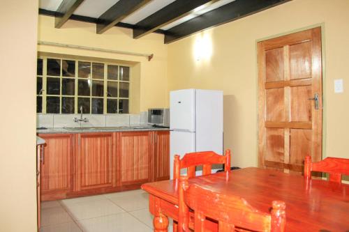 a kitchen with a wooden table and a white refrigerator at Mapelepele Cottage in Simunye