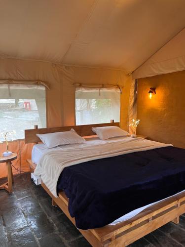 a bedroom with a large bed in a tent at H2H Bir l Nature Camps in Bīr