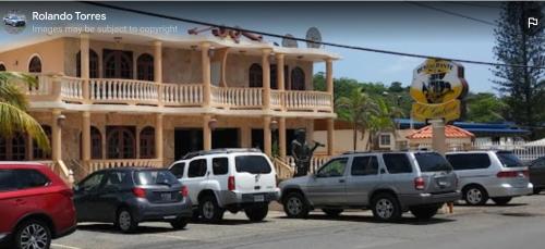 a group of cars parked in a parking lot in front of a building at Yaeliz Front Beach in Aguada