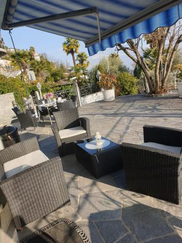 a patio with chairs and tables and a blue umbrella at Casa ALMA in Brione sopra Minusio