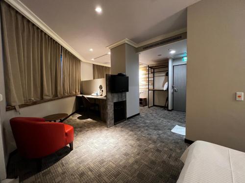 a hotel room with a red chair and a television at East Dragon Hotel in Taipei