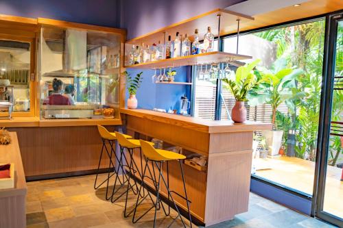 a bar in a restaurant with yellow stools at The Cottage Suvarnabhumi in Lat Krabang
