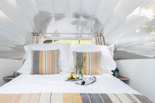 a bedroom with a bed with white sheets and pillows at The 1956 Vintage American Airstream in Dittisham