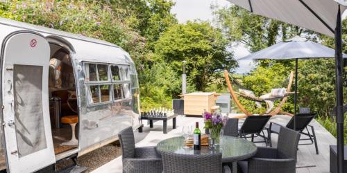 an rv with a table and chairs and an umbrella at The 1956 Vintage American Airstream in Dittisham