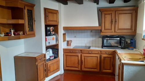 - une cuisine avec des placards en bois et un four micro-ondes dans l'établissement Gite Lilas Sensation, à Thury