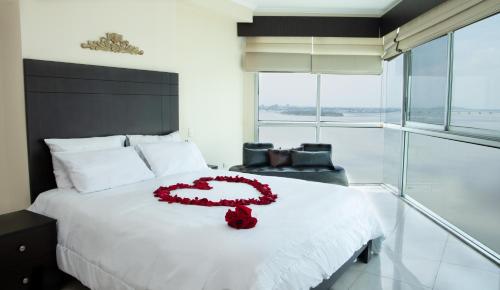a bedroom with a white bed with a red flower on it at Departamento Riverfront 2, Puerto Santa Ana, Guayaquil in Guayaquil
