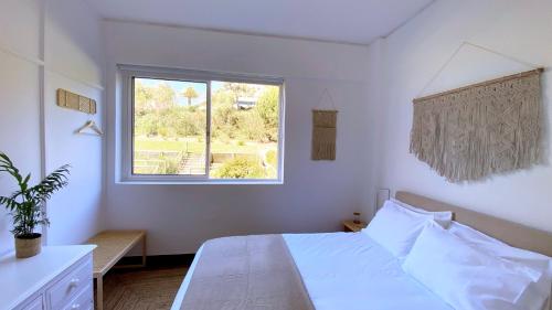 a bedroom with a white bed and a window at Estoril Sunny Apartment in Estoril