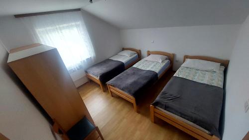 3 camas en una habitación pequeña con ventana en Apartma ASJA en Brežice