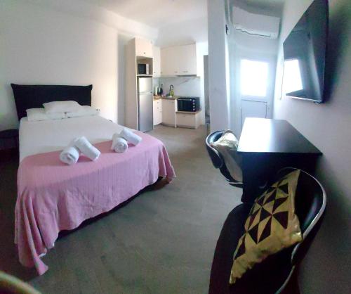 een slaapkamer met een bed met een roze deken en een tafel bij demis Mykonian soul 2 in Platis Yialos Mykonos