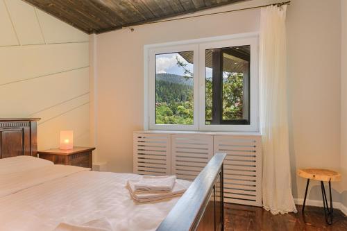 a bedroom with a bed and a window at Blend Mountain Villa in Buşteni