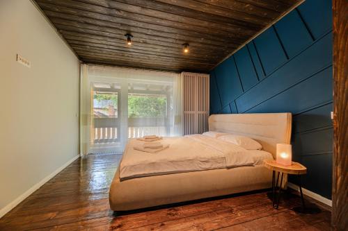 a bedroom with a large bed with a blue wall at Blend Mountain Villa in Buşteni
