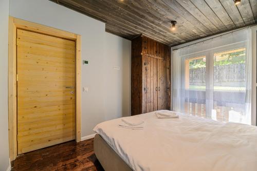 a bedroom with a large bed and a wooden door at Blend Mountain Villa in Buşteni