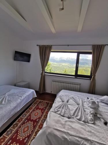a bedroom with two beds and a large window at Belvedere Resort Moieciu in Moieciu de Jos