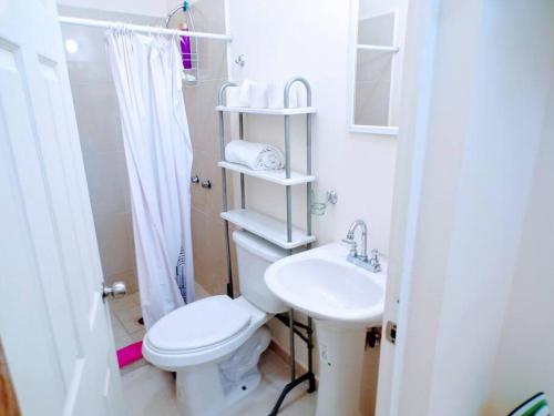 a white bathroom with a toilet and a sink at Loft 25 excelente y comodo, cerca del vado del rio, consulado,CAS, galerias mall , cama queen , cocineta in Hermosillo