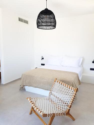 a bedroom with a bed and a rattan chair at myLithos Suites in Monolithos