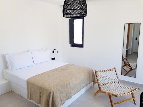 a bedroom with a bed and a chair and a mirror at myLithos Suites in Monolithos