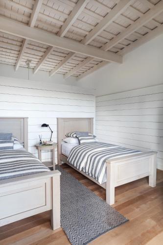 two beds in a bedroom with white walls and wooden floors at Casa Chic Carmelo in Carmelo