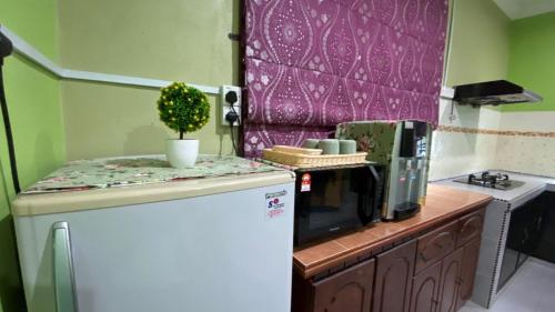 a small kitchen with a refrigerator and a microwave at Seri Idaman Guest House (Pasir Mas) in Kampong Taman