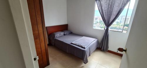 ein kleines Schlafzimmer mit einem Bett und einem Fenster in der Unterkunft Hermoso apartamento, con todas las comodidades. in Medellín