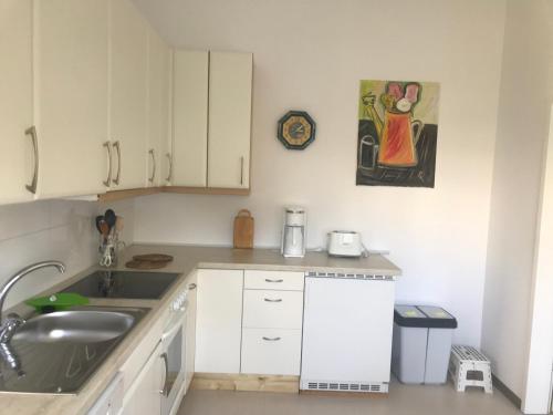 a small kitchen with white cabinets and a sink at Haus Bergstrasse in Stolberg