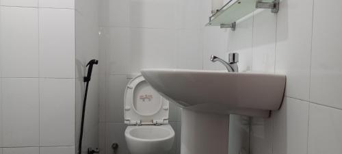 Baño blanco con lavabo y aseo en Shady transit hotel, en Katunayake