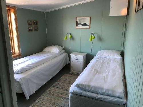 two beds in a room with green walls at Skjæret rorbu in Stamsund