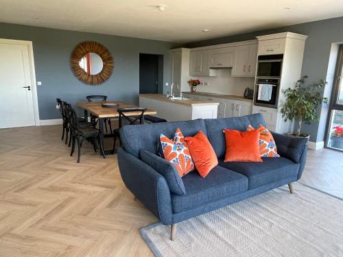 a blue couch with orange pillows in a living room at Garryvoe - Ballycotton Bay & Island View in Garryvoe