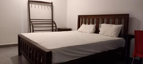 Una cama con sábanas blancas y una silla en una habitación en Shady transit hotel, en Katunayake