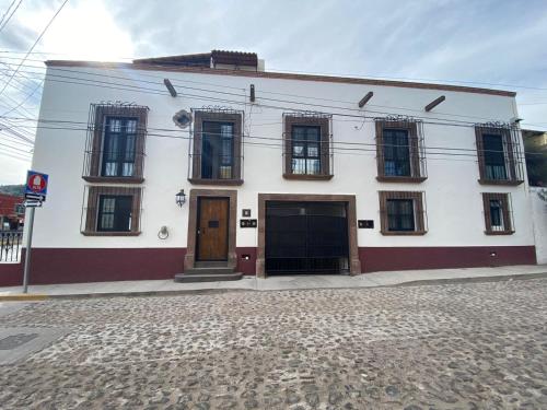 a white building with brown doors on a street at Hotel La Lejona in San Miguel de Allende