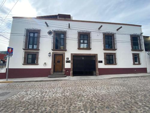 un bâtiment blanc avec des portes brunes dans une rue dans l'établissement Hotel La Lejona, à San Miguel de Allende
