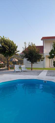 a blue swimming pool in front of a house at CANAVESES RIVER HOUSE - ALOJAMENTO RURAL in Marco de Canaveses