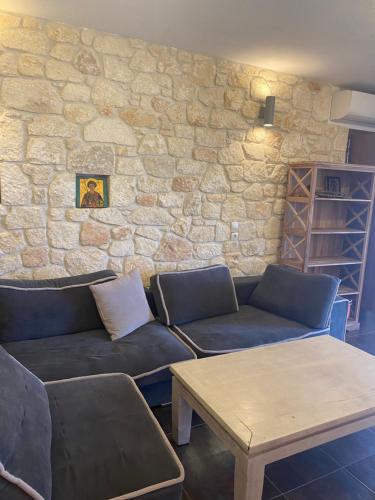 - un salon avec un canapé et un mur en pierre dans l'établissement FRENKI APARTMENT BY THE SEA, à Siviri