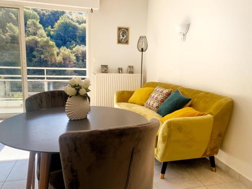 un soggiorno con tavolo e divano giallo di Villa Madeleine - Résidence Services Seniors a Nizza