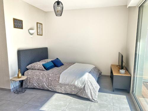una camera da letto con un letto con cuscini blu e una TV di Villa Madeleine - Résidence Services Seniors a Nizza