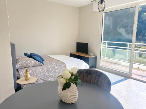 Un dormitorio con una mesa con un jarrón de flores. en Villa Madeleine - Résidence Services Seniors, en Niza