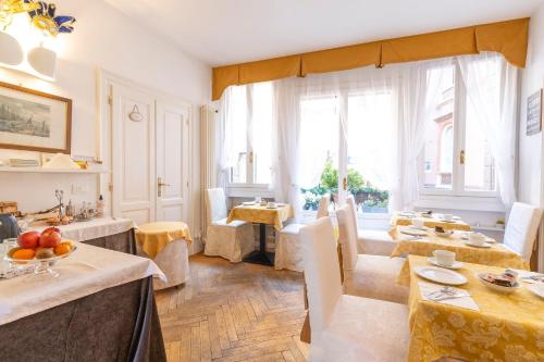 uma sala de jantar com mesas, cadeiras e janelas em Hotel Casa Petrarca em Veneza