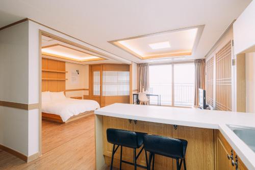 a room with a bed and a kitchen with chairs at O2Heal resort in Jeju