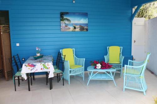 d'une terrasse avec une table et des chaises et un mur bleu. dans l'établissement Bougainvilliers, à Schœlcher