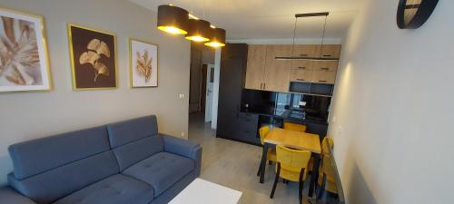 a living room with a blue couch and a kitchen at Apartament BARCELONA in Krakow