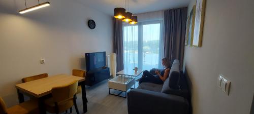 a woman sitting on a couch in a living room at Apartament BARCELONA in Krakow
