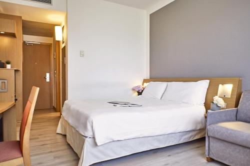 a bedroom with a large white bed and a chair at Living Place Hotel in Villanova