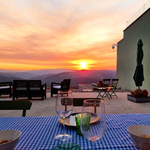 a table with wine glasses and a sunset in the background at Vald'arêgos - Douro in Resende