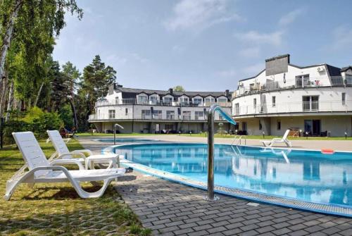 a swimming pool with two lounge chairs next to a building at Apartament Baltic Star in Pobierowo