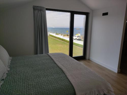 sypialnia z łóżkiem i dużym oknem z widokiem na ocean w obiekcie POLAS BEACH LOFT w mieście Nois