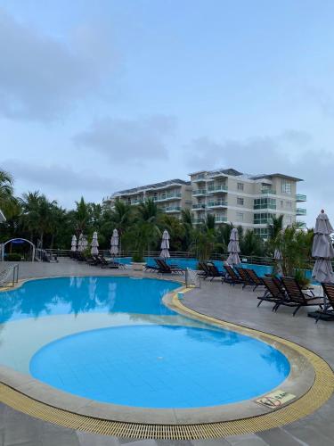 a pool with chairs and umbrellas in a resort at Paradise Condotel Mũi Né - Căn hộ nghỉ dưỡng Ocean Vista in Ấp Ngọc Hải