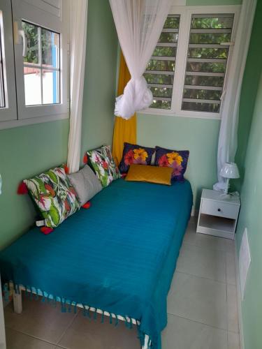 a bedroom with a blue bed in a room with windows at Bougainvilliers in Schœlcher