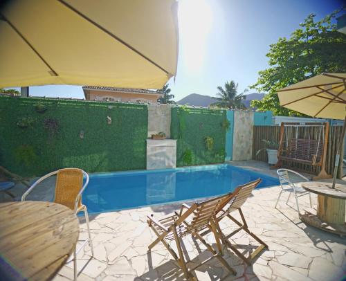 聖塞巴斯蒂安的住宿－Residencial Águas de Bare，一个带椅子和桌子的游泳池以及一把遮阳伞