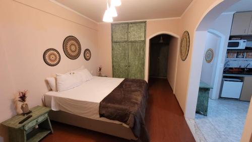 a bedroom with a large bed and a kitchen at FLAT CONJUGADO CAVALINHO BRANCO o in Águas de Lindoia