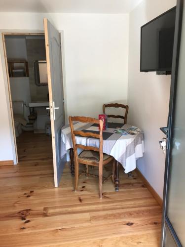 a dining room with a table and chairs and a television at Chambre d'hôte aux Pivoines in Nistos