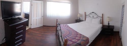 een slaapkamer met een bed en een flatscreen-tv bij De Alamo hostel in Rosarito